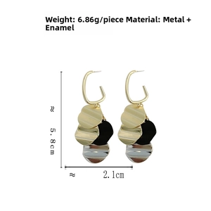 Macro detail of multi-layered gold, silver, and black wavy metal disc tassel earrings