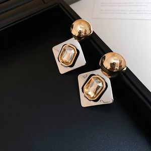 Détail macro de boucles d'oreilles géométriques avec cristal champagne et boîte à bijoux