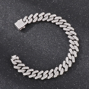 Detailansicht eines silbernen Panzerarmbands mit glitzernden Strasssteinen auf grauem Grund