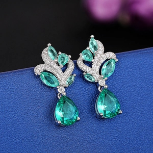 Macro detail of silver drop earrings with emerald green pear-cut stones and white zircons