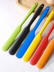Detailed view of six colorful silicone spatulas arranged on a white marble surface