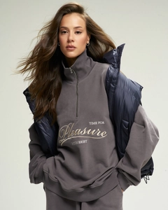 Detail of grey half-zip sweatshirt with embroidery and shiny navy puffer vest