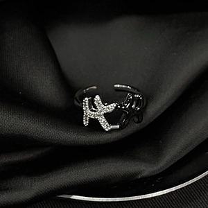 Macro shot of an adjustable moon-shaped ring featuring pavé crystals on a black silk backdrop