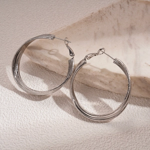 Detailed macro view of large silver geometric hoop earrings with brushed metal texture finish
