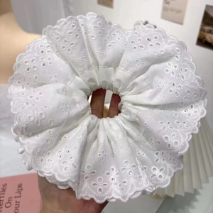 Close-up of white cotton lace scrunchie with delicate floral embroidery detail