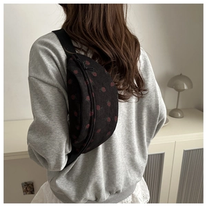 Detail of black corduroy waist bag featuring red strawberry print and nylon strap