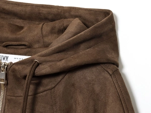 Detailed macro view of dark brown faux suede texture on hooded bomber jacket with zipper