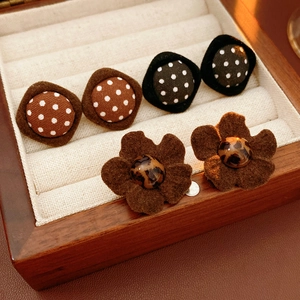 Close-up of retro fabric polka dot and flower earrings on velvet lining inside a wooden box