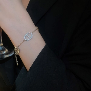 Detail of gold-plated oval CD charm bracelet with cubic zirconia on a female wrist