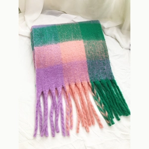 Detailed view of plaid scarf fringe in soft green, pink and purple checkered wool fabric