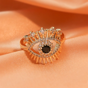 Detail shot of a gold devil eye ring with pave zircons on warm silk fabric background