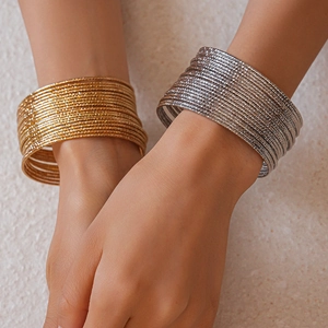 Dettaglio di 20 bracciali a strati in oro e argento con finitura metallica strutturata