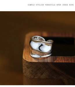 Macro shot of silver twisted metal ring with wavy design on a wooden display stand