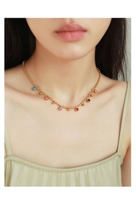 Close-up of golden bean necklace with colorful charms on a model's collarbone