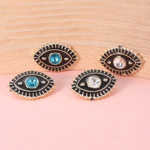 Detail of evil eye stud earrings featuring gold-plated frames and clear blue crystals