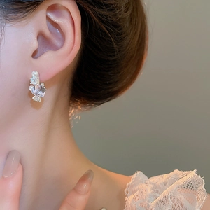 Macro view of crystal cube stud earring with pearl accents worn by a model