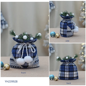 Detailed views of a blue plaid Christmas gift bag with pine needles and plush pompoms