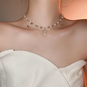 Detail of double-layer necklace with pearls, pink stones, and a diamond flower pendant