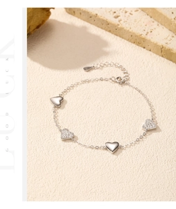 Close-up of s925 silver heart bracelet with polished charms and sparkling zircons