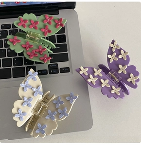 Detail of butterfly hair claws with floral accents in mint, purple and cream colors