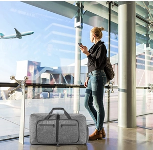 Large gray travel bag with dual pockets shown in a bright airport terminal setting