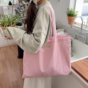 Pink and white striped canvas tote bag detail on shoulder in a bright kitchen setting
