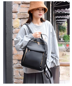 Detailed view of women's black nylon backpack featuring gold zippers and front pocket