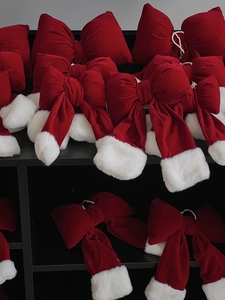 Detail of red velvet Christmas bows with white plush pom-poms on a display rack