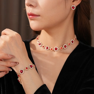 Primo piano del set gioielli vintage dorati con pietre cuore rosse e zirconi su modella
