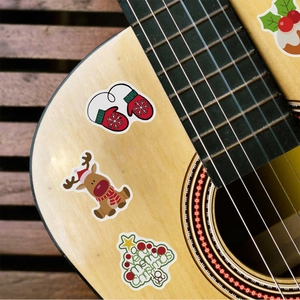 Detail of waterproof Christmas graffiti stickers showing reindeer and tree on a guitar