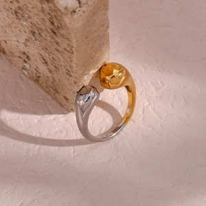 Detail of two-tone gold and silver open ring with teardrop ends on beige stone