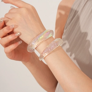 Macro shot of iridescent wavy acrylic bangles showing colorful texture and light refraction