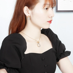 Close-up of rose gold necklace and earrings set with roman numerals worn by a model
