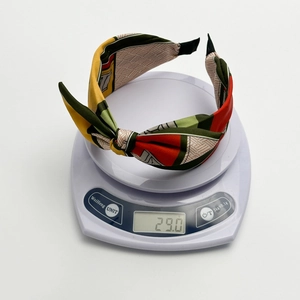 Knotted satin wide headband with geometric print on a white scale showing weight