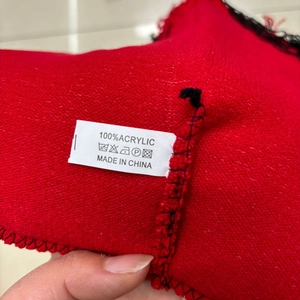 Macro view of the 100% acrylic fabric label on a red knitted winter beanie cap