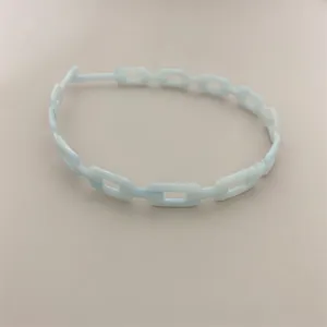 Detail of light blue chain-link headband with smooth resin finish and minimalist design