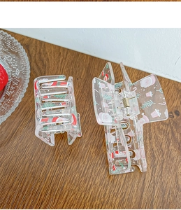 Detailed macro view of large acrylic hair claws with cute festive Santa Claus prints