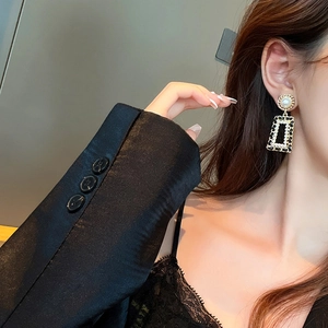 Detail of vintage gold geometric rectangular earrings with pearls and black leather texture