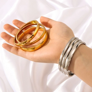 Minimalistische goldene und silberne Titanstahl-Armreifen auf Satin am Handgelenk