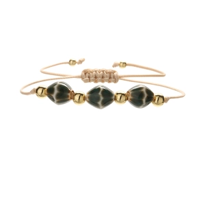 Detailed close-up of handmade woven rope bracelet with geometric ceramic rhombus beads