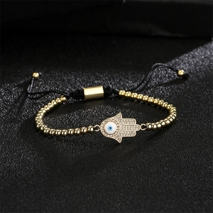 Détail du bracelet Hamsa doré avec œil bleu et cordon noir ajustable en gros plan