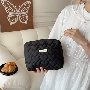Close-up of black quilted makeup bag with heart patterns and woven brand label