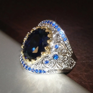 Dettaglio macro di anello vintage in argento con zaffiro blu ovale e intagli elaborati