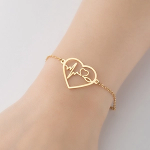Goldenes Edelstahl-Armband mit Herz-Ekg-Anhänger am Handgelenk einer Frau präsentiert