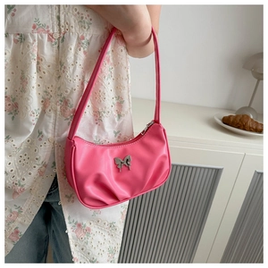 Detailed side view of a pink shoulder bag with a silver butterfly ornament on a model
