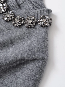 Detail of floral black rhinestones on a grey knitted round neck short sleeve top
