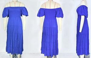 Dettaglio dell'abito blu con spalle scoperte, busto a punto smock e gonna a balze
