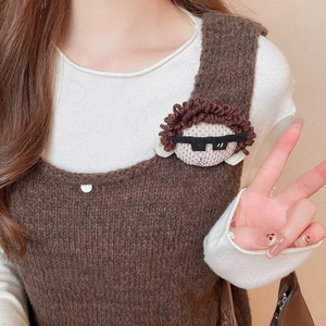 Detailed view of handmade knitted doll brooch with brown curly hair and sunglasses