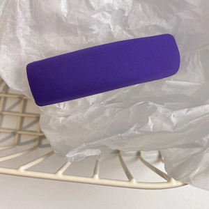 Close-up of a purple fabric sponge hair clip with diagonal twill texture on tissue paper