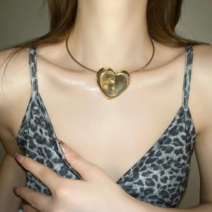 Close-up of golden heart pendant necklace worn by a model in a minimalist style